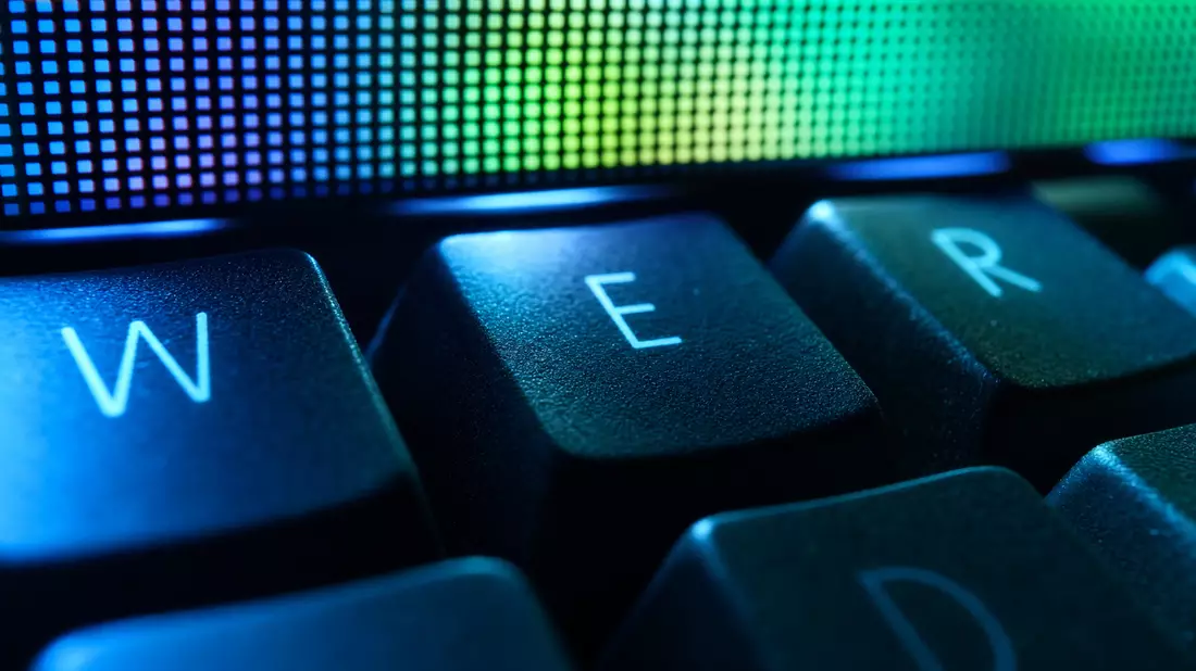Makroaufnahme von Tastaturtasten mit unscharfem leuchtendem Pixelbildschirm im Hintergrund