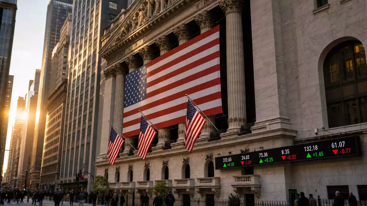 Editorial-Foto der NYSE-Fassade mit US-Flaggen und digitaler Kurstafel im Sonnenlicht
