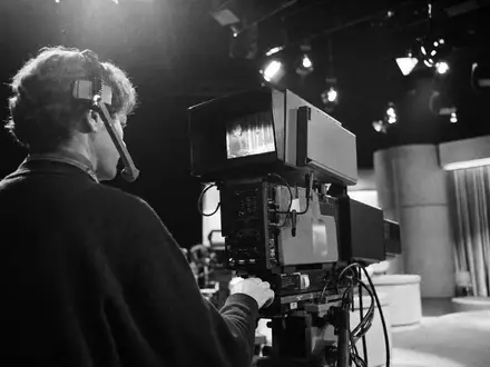 Paramount Global (US92556V1061) Kameramann im generischen TV-Studio, Schwarz-Weiß-Reportagestil zeigt authentische Medienbranche eindrucksvoll - Foto: THN