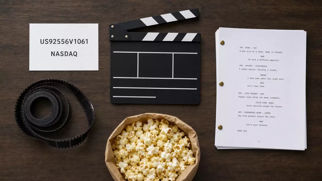 Flatlay-Aufnahme mit ISIN-Karte, Klappe, Filmrolle, Drehbuch und Popcorntüte auf Holztisch