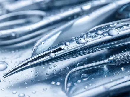 Steris plc IE00BFY8C754 zeigt in einer Makroaufnahme glänzende chirurgische Edelstahlinstrumente mit feinen Wassertropfen - Foto: THN