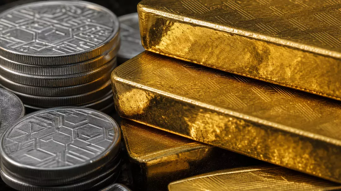Makroaufnahme von glänzenden Goldbarren und Silbermünzen im dramatischen Licht