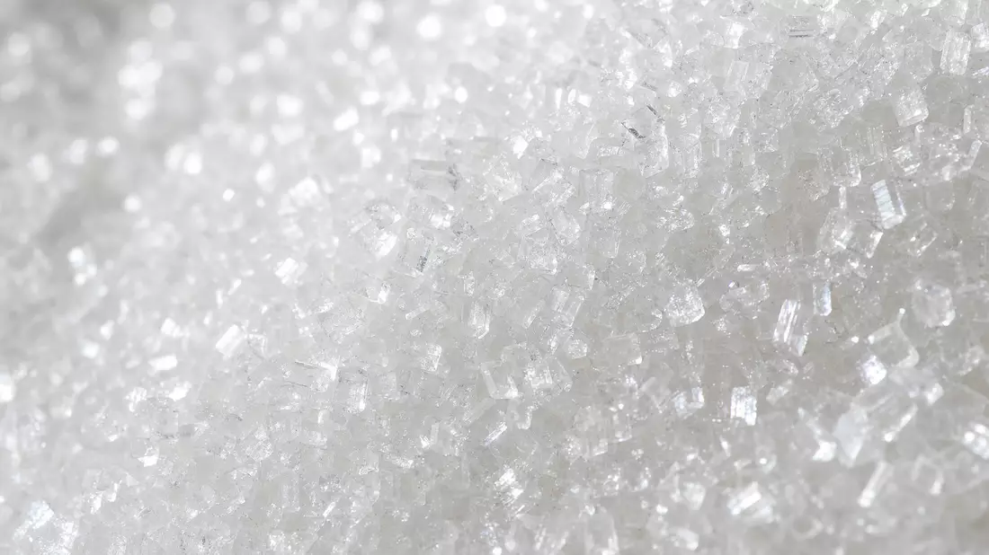 Makroaufnahme von glitzernden weißen Zuckerkristallen in extremer Nahaufnahme