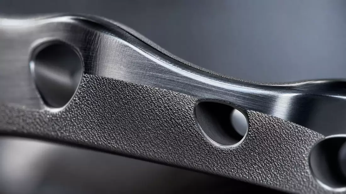 Makrofoto einer polierten Titan-Implantatoberfläche mit feiner Textur und Lichtreflexen