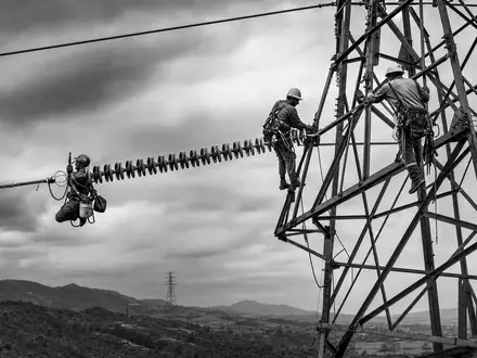 Southern Company US8425871071 dokumentiert Techniker bei Wartungsarbeiten an Hochspannungsmasten in dramatischer SchwarzweiĂ-Reportage-Fotografie - Foto: THN