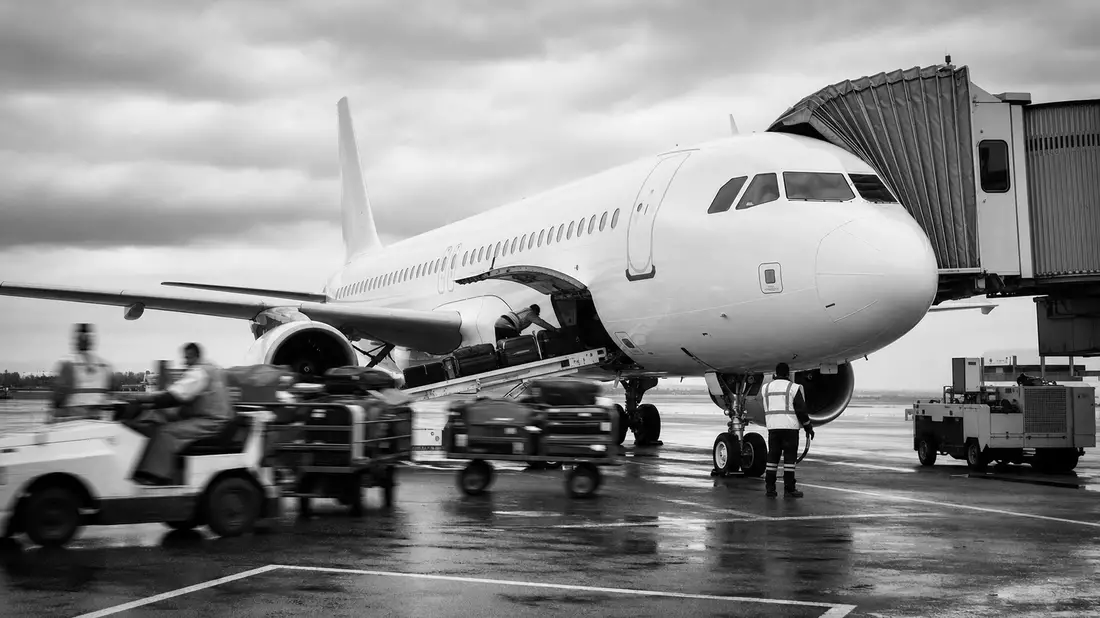 Schwarz-Weiß-Reportagefoto von Bodenpersonal beim Flugzeug-Boarding am Gate