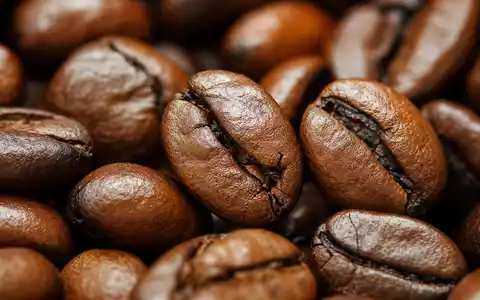 Starbucks Corp. US8552441094 fokussiert detailreiche Makroaufnahme gerösteter Kaffeebohnen mit feiner glänzender Oberflächenstruktur - Foto: THN