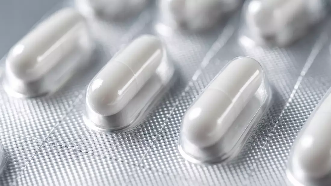 Extreme Makroaufnahme weißer Kapseln in Silberfolie-Blisterpackung mit Bokeh-Hintergrund