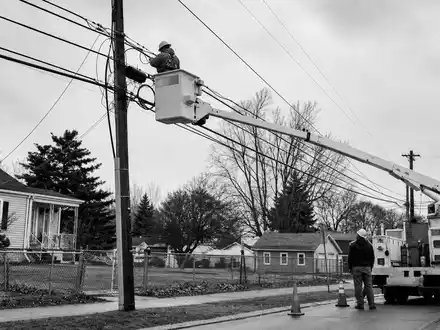 Liberty Broadband (US5303071071): dokumentarische Schwarzweiß-Reportage zeigt Techniker beim Verlegen von Breitbandkabeln in Wohnstraße - Foto: THN