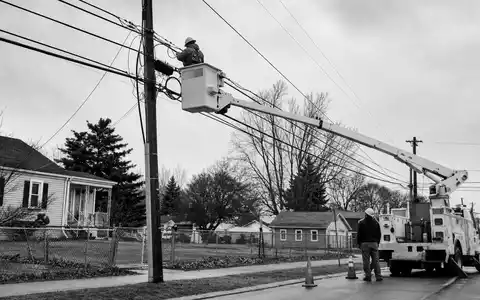 Liberty Broadband (US5303071071): dokumentarische Schwarzweiß-Reportage zeigt Techniker beim Verlegen von Breitbandkabeln in Wohnstraße - Foto: THN