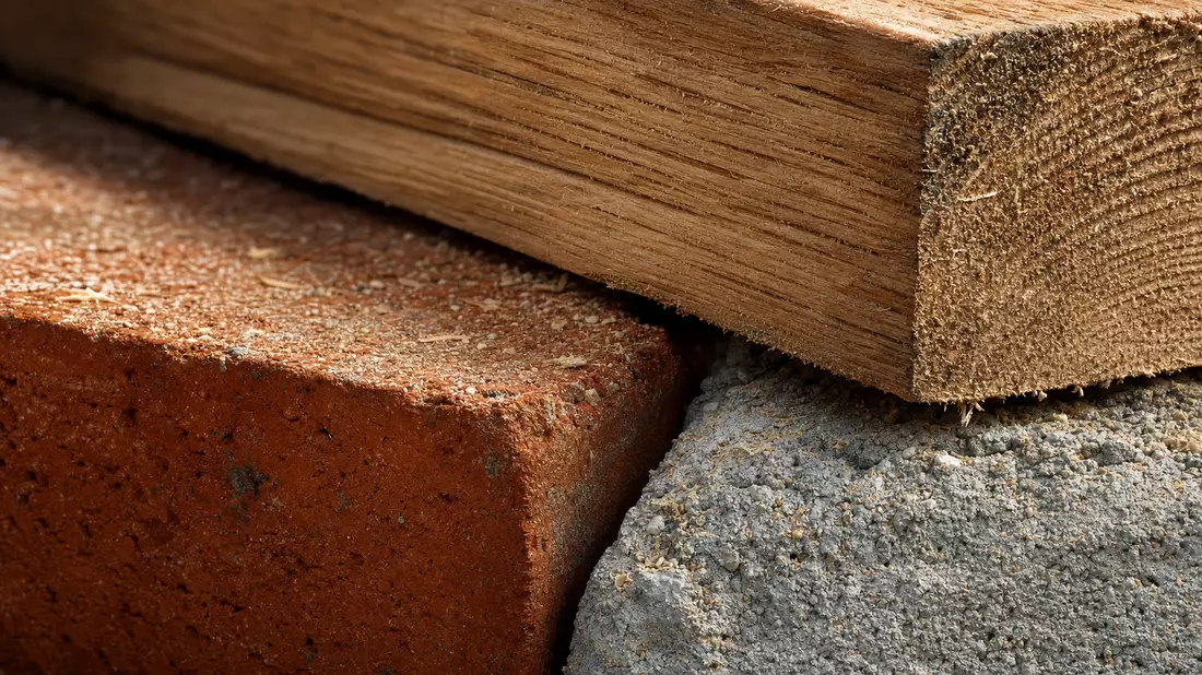 Makroaufnahme von Holzbalken, rotem Ziegelstein und rauer Betonoberfläche
