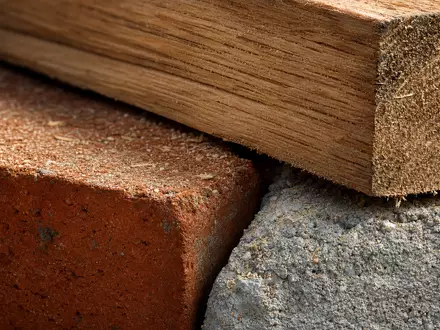 Lennar Corporation (ISIN US5260571048) zeigt eine Makroaufnahme von Baumaterialien wie Holz, Ziegel und Beton - Foto: THN