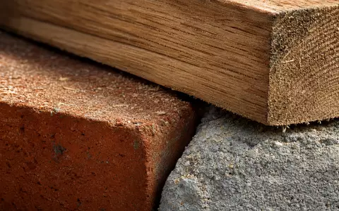Lennar Corporation (ISIN US5260571048) zeigt eine Makroaufnahme von Baumaterialien wie Holz, Ziegel und Beton - Foto: THN