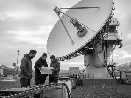 Schwarzweiss-Reportage dokumentiert fuer Leidos Holdings ISIN US5253271028 eine Satellitenanlage mit Ingenieuren im freien Gelaende - Foto: THN