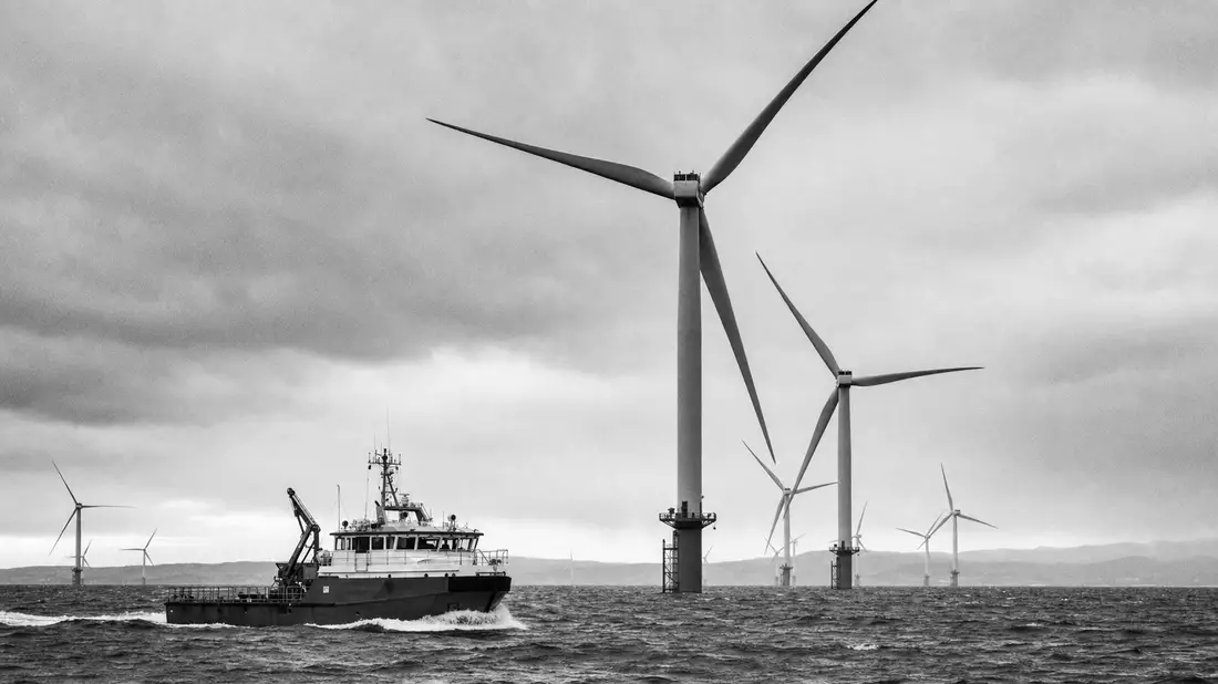 Schwarzweiß-Reportagefoto eines Offshore-Windparks mit Serviceschiff vor Schottland