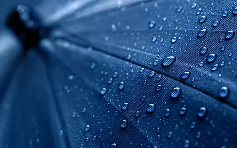Sampo Oyj (ISIN FI0009003305) steht sinnbildlich für Schutz, dargestellt durch Wassertropfen auf Regenschirmstoff - Foto: THN