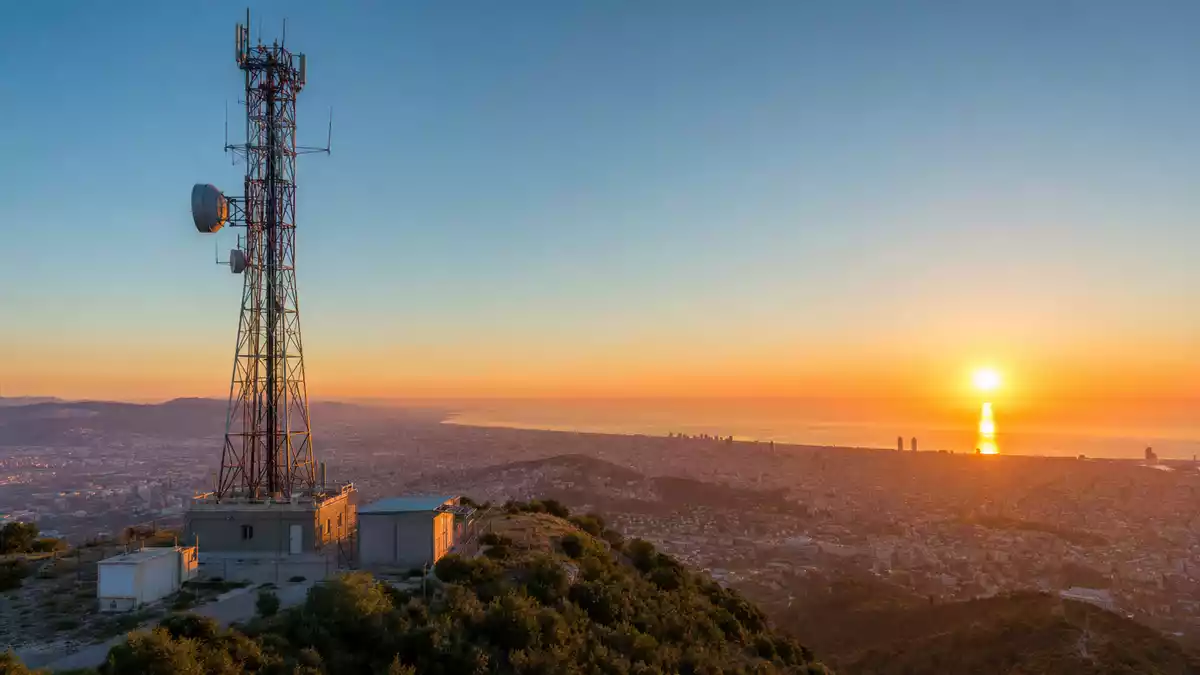 Sendemast bei Sonnenuntergang über Barcelona, Symbolbild für Cellnex Telecom S.A
