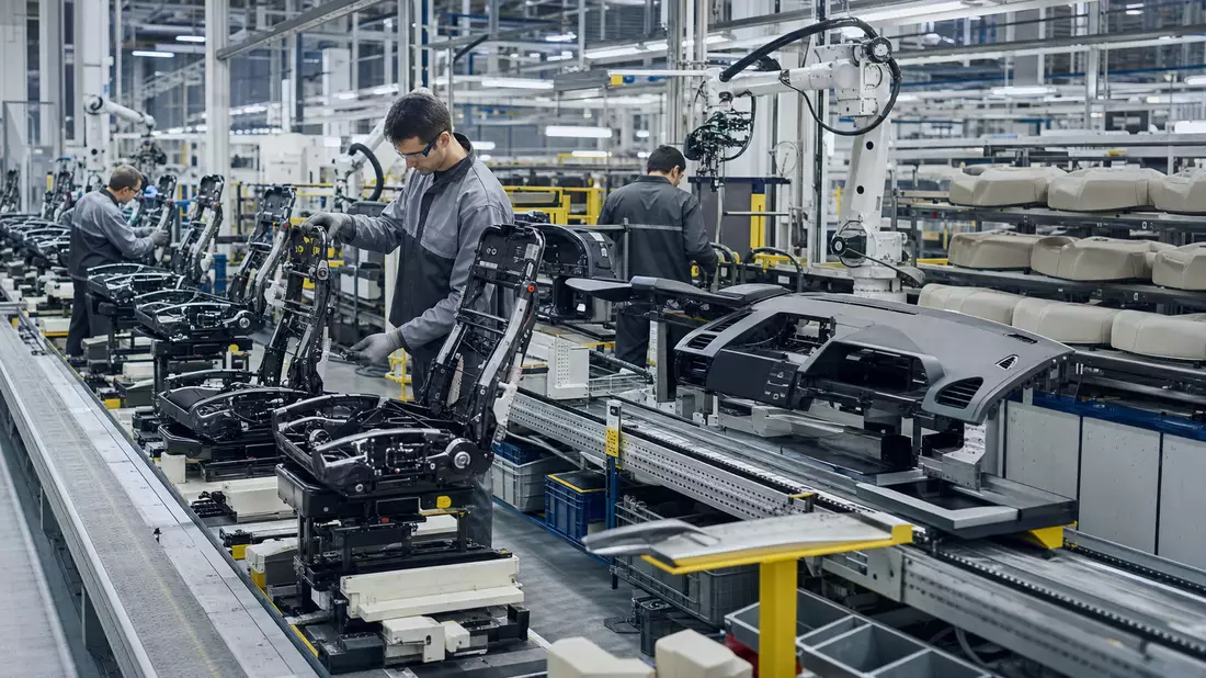 Arbeiter montieren Autositze und Armaturenbretter in moderner Fertigungshalle eines Automobilzulieferers