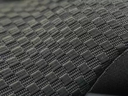 Makroaufnahme von Autositz-Stoffgewebe illustriert Materialkompetenz von Forvia SE, ISIN FR0000121147, im Interieurgeschäft - Foto: THN