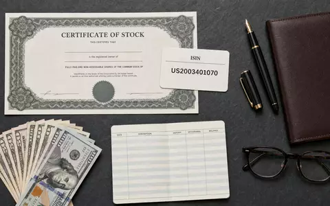 Comerica Inc. Flatlay mit Aktienzertifikat US2003401070 Füller Dollarnoten Leder Portfolio auf Schiefer - Foto: THN