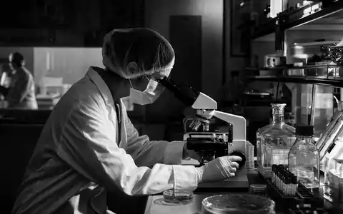 Gilead Sciences ISIN US3755581036 Schwarzweiß-Reportage Forscherin untersucht Zellkulturen am Mikroskop im Labor - Foto: THN