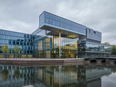ING Groep N.V. Bankzentrale NL0011821202 als modernes Glasgebäude am Amsterdamer Kanal bei bewölktem Himmel - Foto: THN