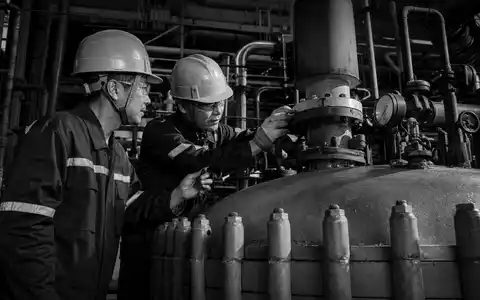Celanese Corp. Schwarzweiß-Reportage zeigt zwei Chemiearbeiter beim gemeinsamen Inspizieren eines Polymer-Reaktors US1510201049 - Foto: THN