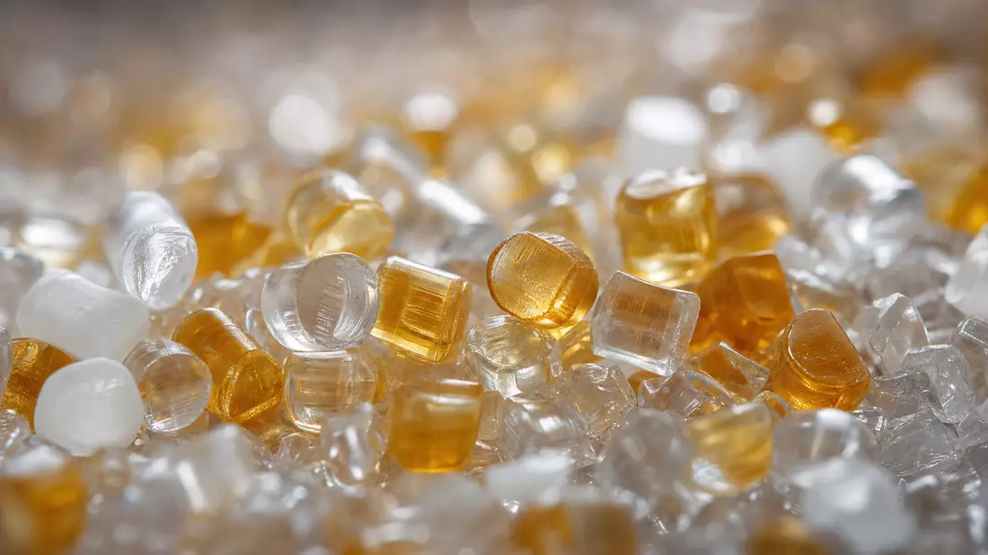 Extreme Nahaufnahme transluzenter Kunststoffgranulate in Amber und Weiß mit weichem Hintergrund