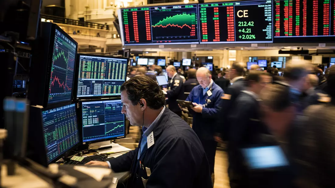 Redaktionsfoto des NYSE-Handelsraums mit Tradern und Aktien-Charts auf mehreren Bildschirmen