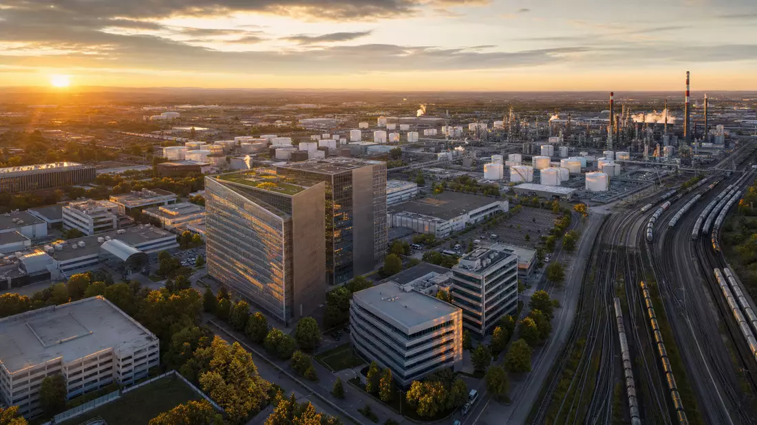 Fotorealistischer Konglomerat-Campus mit Bürotürmen, Gleisen und Industrie bei Sonnenuntergang