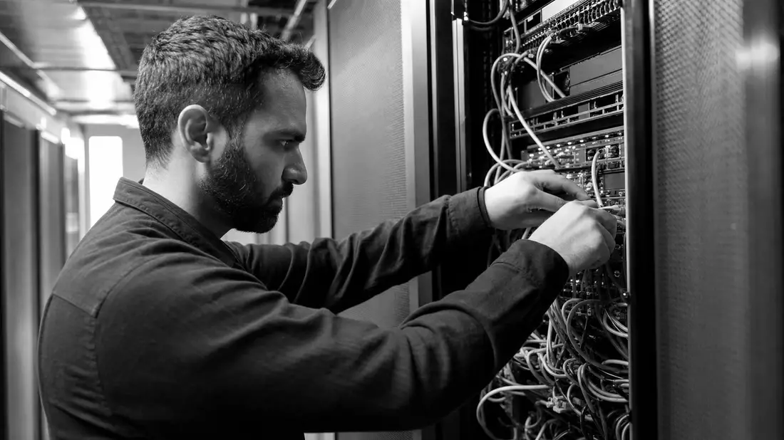 Schwarzweiß-Reportage eines IT-Technikers beim Einbauen von Serverkabeln