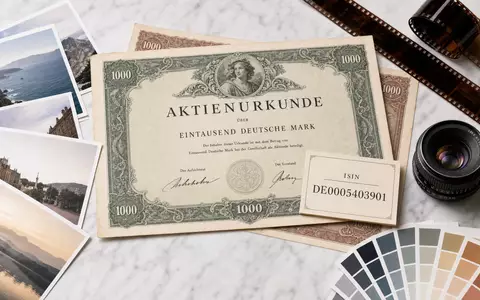 CEWE Stiftung & Co. KGaA DE0005403901 Flatlay mit Aktien-Zertifikat, ISIN-Karte und Fotoprodukten auf Marmor - Foto: THN