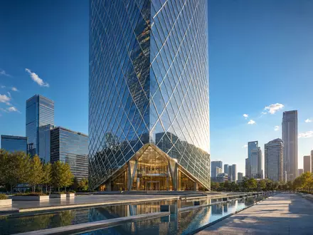 HOCHTIEF AG Hochhausrender DE0006070006 zeigt modernes Glasgebäude im Finanzviertel mit Reflektionsbecken bei Sonnenlicht - Foto: THN