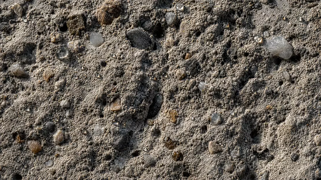 Makro-Detailaufnahme HOCHTIEF AG Betonoberfläche mit Kieselsteinen und Wassertropfen