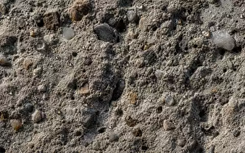 HOCHTIEF AG Betonoberfläche DE0006070006 als extreme Makroaufnahme mit Zuschlagsstoff Zementmatrix und Wassertropfen - Foto: THN