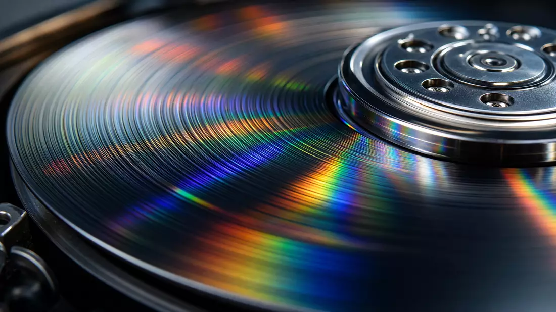 Extreme Makroaufnahme einer spiegelnden Magnetplatte mit regenbogenfarbenen Lichtreflexionen
