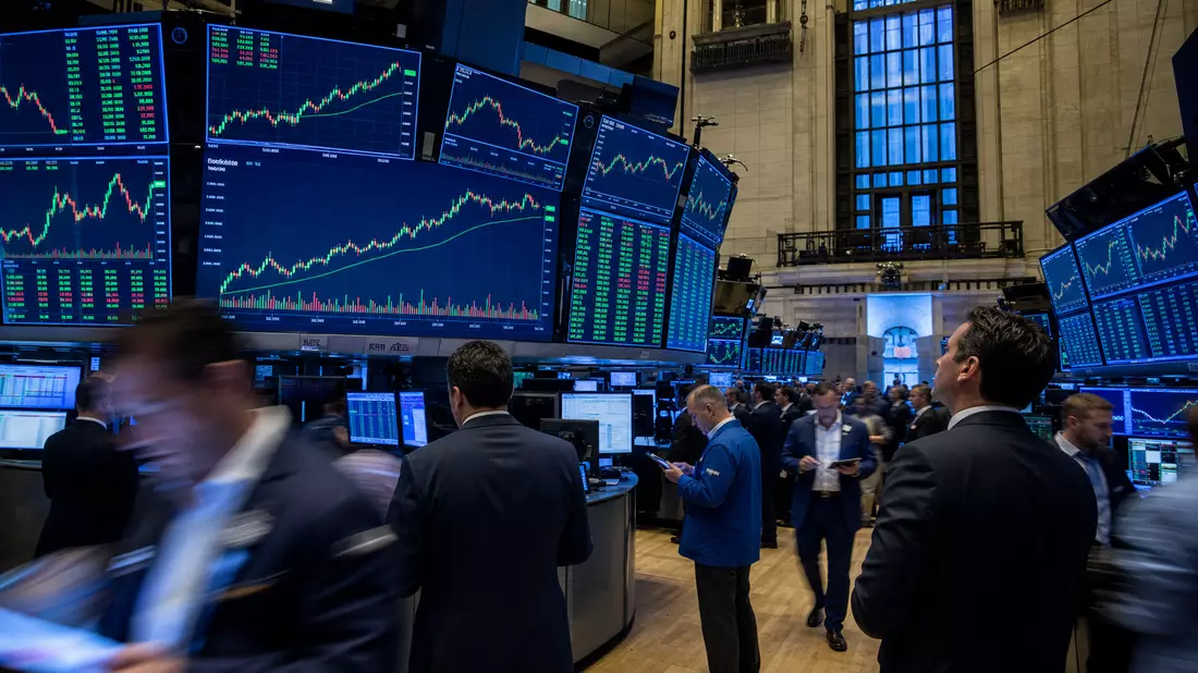 Editorial-Aufnahme eines Trading-Floors mit großen Bildschirmen und Aktienkursdiagrammen