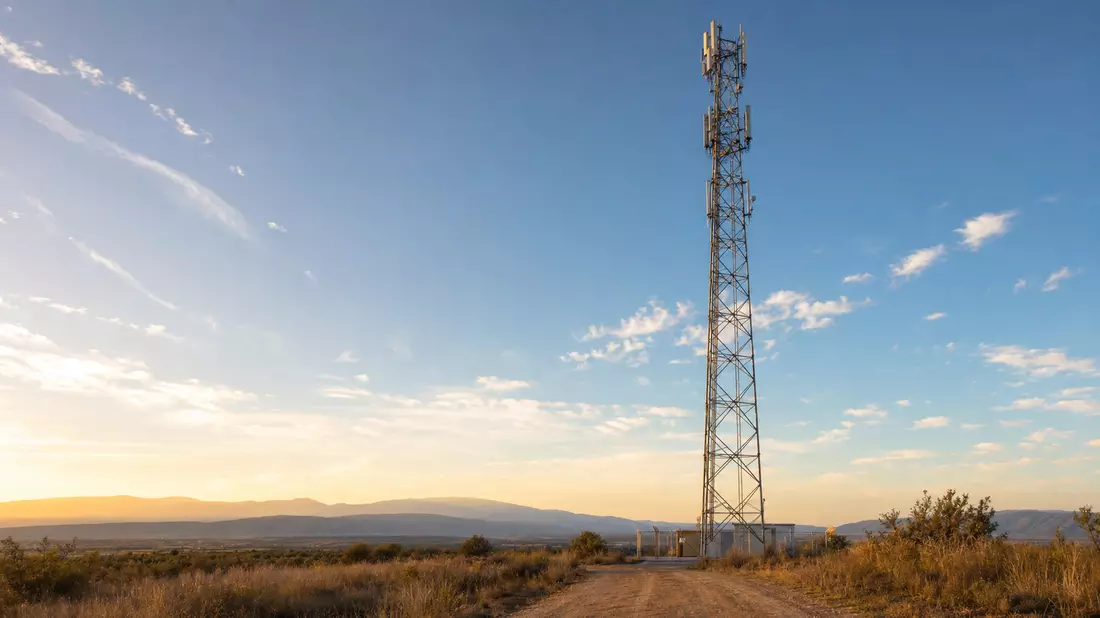 Mobilfunk-Sendemast mit Antennen in weiter Landschaft bei goldenem Abendlicht