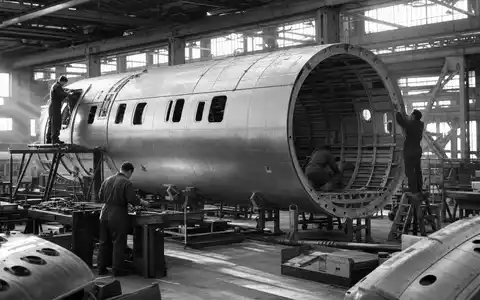 Airbus SE (NL0000235190) präsentiert eine dokumentarische Schwarzweiß-Reportage-Aufnahme eines Flugzeugrumpf-Segments in der Fertigung - Foto: THN