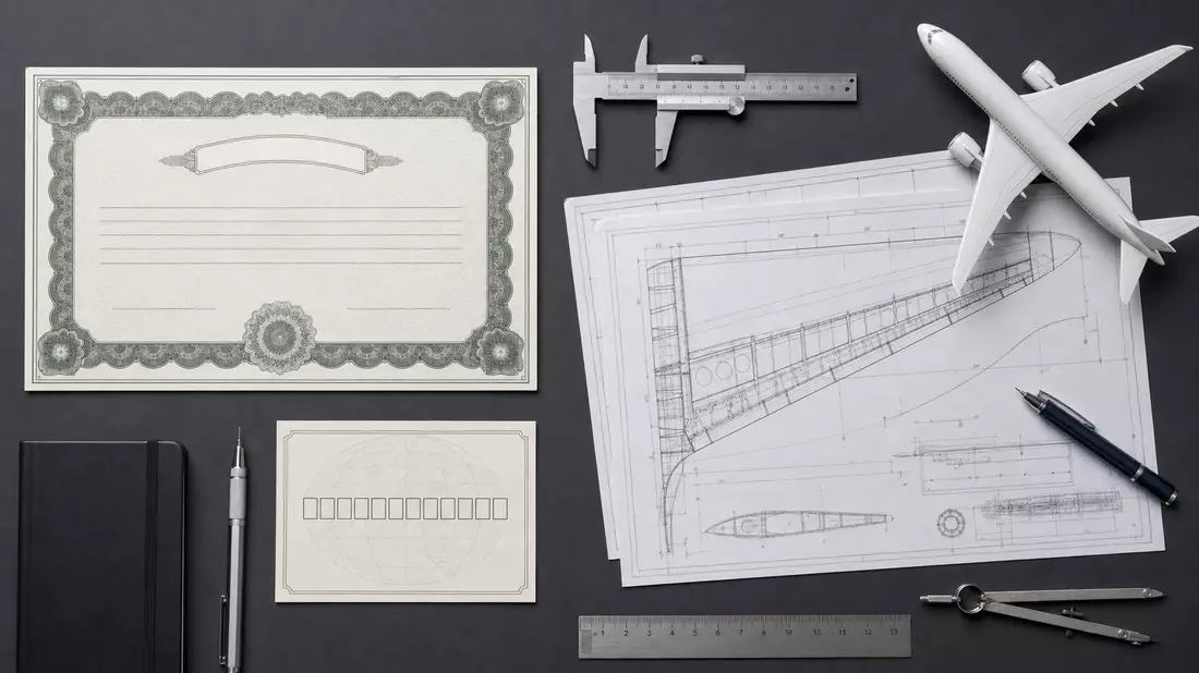 Flatlay-Arrangement mit Aktienzertifikat, ISIN-Karte und Luftfahrt-Werkzeugen auf grauem Tisch