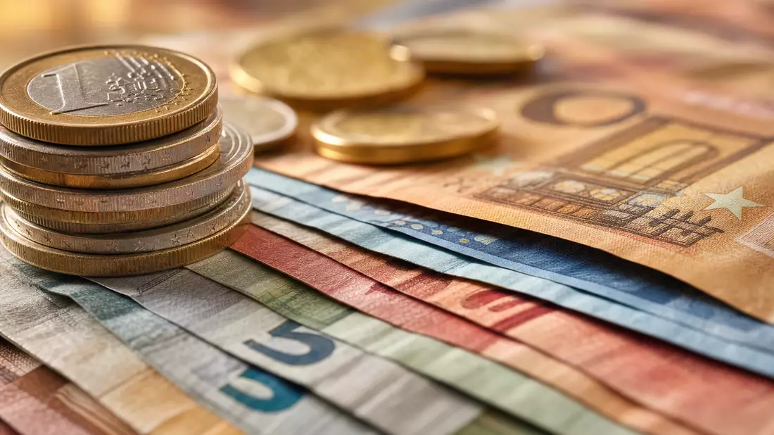 Makroaufnahme gestapelter Euro-Banknoten und Münzen mit unscharfem Hintergrund