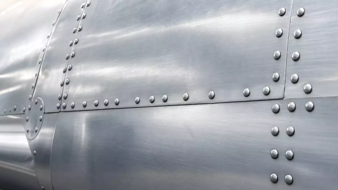 Nahaufnahme gebürsteter Aluminium-Rumpfhaut mit Nieten