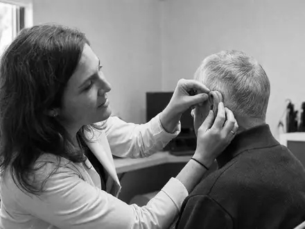Schwarzweiß-Reportagefoto dokumentiert eine authentische Hörtest-Szene, thematisch verbunden mit Amplifon S.p.A., ISIN IT0004056880, Gesundheitssektor - Foto: THN