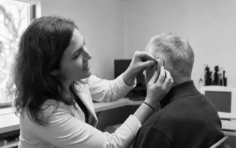 SchwarzweiĂ-Reportagefoto dokumentiert eine authentische Hörtest-Szene, thematisch verbunden mit Amplifon S.p.A., ISIN IT0004056880, Gesundheitssektor - Foto: THN