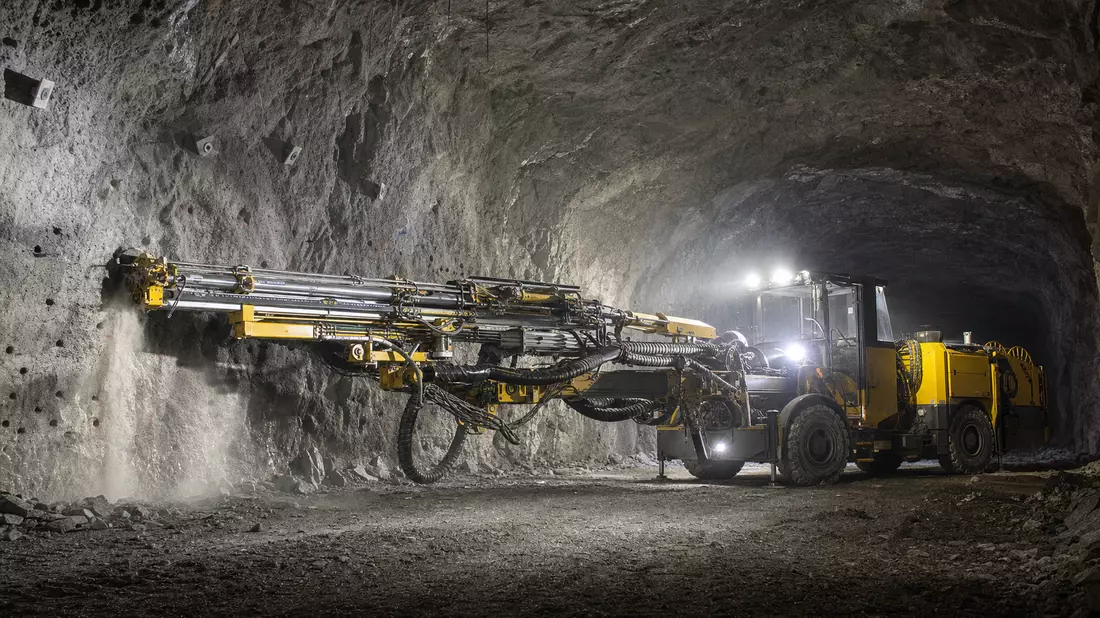 Fotorealistisches Bohrgerät im Felstunnel einer Untertagemine bei Arbeitslicht