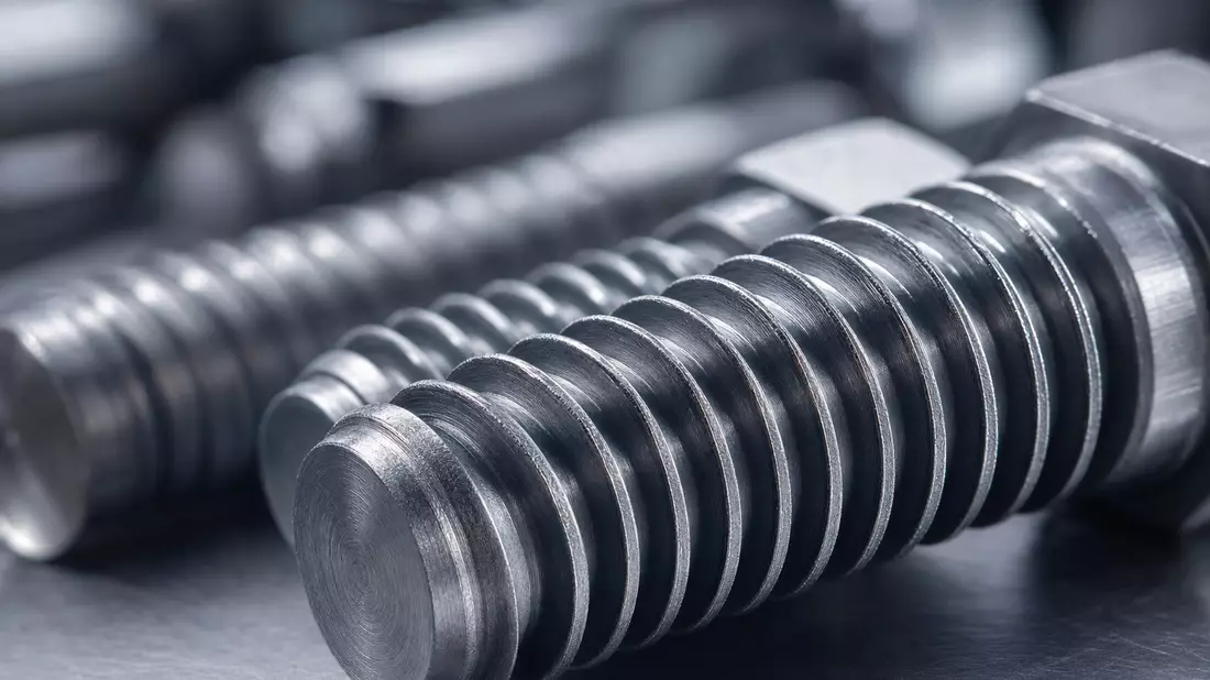 Extreme Makroaufnahme präzisionsgefertigter Stahlschrauben mit scharfen Gewindedetails und Metallstruktur