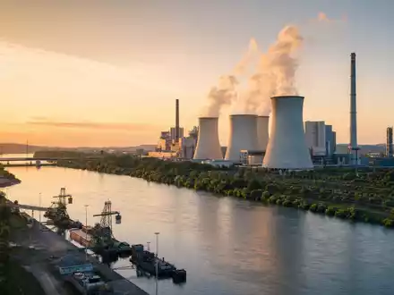 Duke Energy Kraftwerk US26441C2044 am breiten Fluss mit dampfenden Kühltürmen im goldenen Abendlicht - Foto: THN