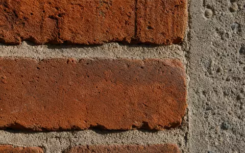 Makroaufnahme von Backstein und Beton zeigt Baumaterial von Persimmon plc GB0030927254 im Detail sehr nah - Foto: THN