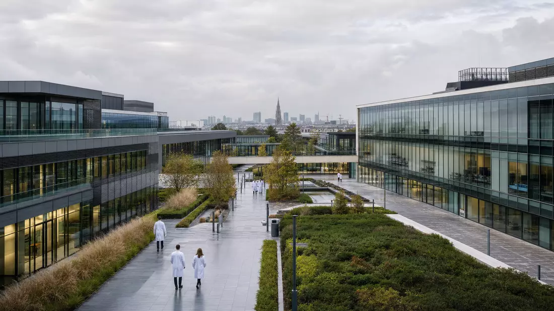 Moderner Biopharma-Forschungscampus mit Glasgebäuden und Laborpersonal in Brüssel bei Tageslicht