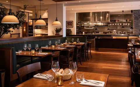 Darden Restaurants US2371941053 zeigt warmes Casual-Dining-Interieur mit Holztischen, Weingläsern und offener Küche - Foto: THN